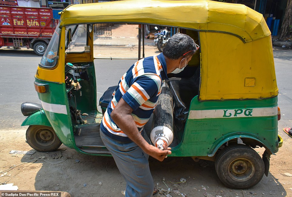 This image has an empty alt attribute; its file name is 42159356-9506681-A_man_carries_an_oxygen_canister_to_his_car_in_West_Bengal_India-a-52_1619271390211.jpg